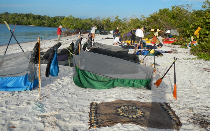 a collection of shelters rest on a sandy beach